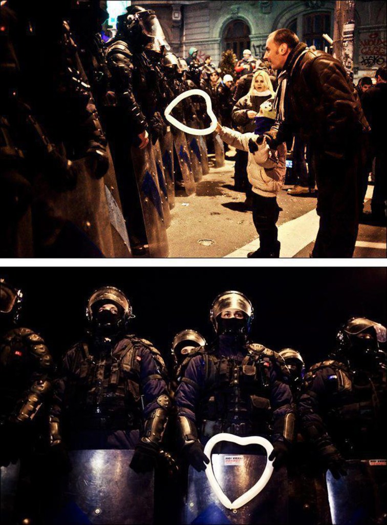 A Romanian child hands a heart-shaped balloon to riot police
