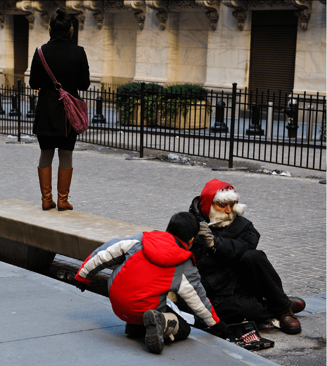 Young boy tips street musician on Wall Street in Manhattan - New York City.