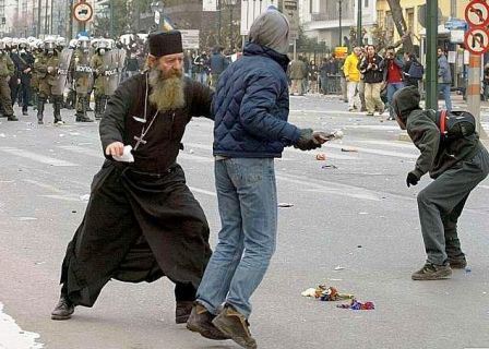 Photo of a priest attempting to stop a rioter from throwing a molotov cocktail at riot police