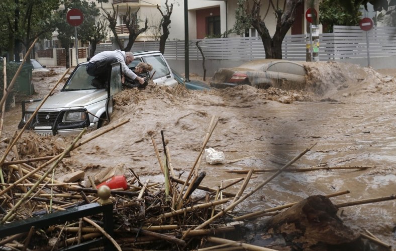 A man rescues a woman from her car on a flooded road in the Athens suburb of Chalandri in February.