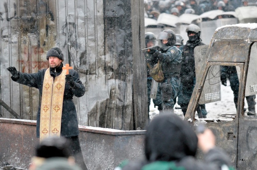 Orthodox priest trying to prevent a clash between demonstrators and the police in Kiev, Ukraine