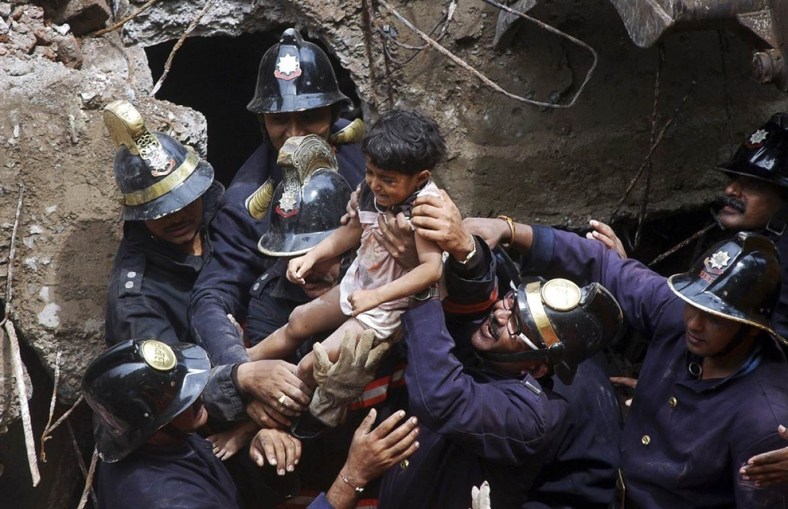 Rescue workers carry a child who was rescued from the rubble at the site of a collapsed residential building in Mumbai, India, in September.