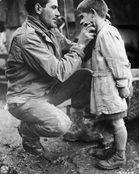 US Army soldier Walton Trohon photographed while cleaning the face of a young French orphan, November 1944