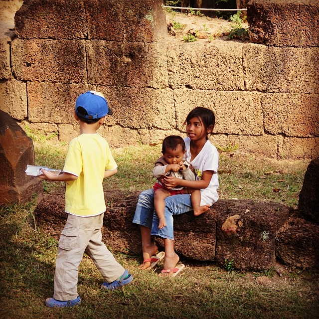 This little Japanese tourist boy giving cookies to the local Cambodian children. 