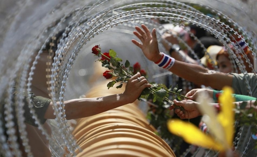 An anti-government protester gives a rose to a Thai soldier at the Defense Ministry during a rally in Bangkok.