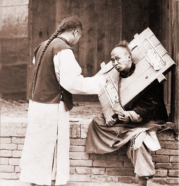 Charitable Chinese man feeding a criminal in a cangue. Petty criminals were sentenced to wear the canque, often for a couple of months, and display themselves in public places.