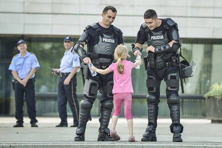 Girl hands water to two officers [Bosnia, 2013]