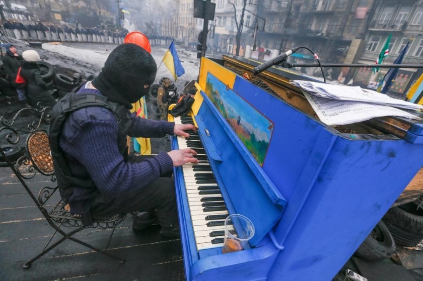 A Ukrainian protester plays piano on a barricade in front of the riot police line, Monday, Feb. 10, 2014