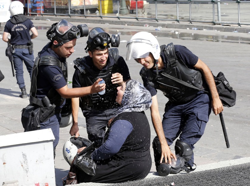 Riot police help a woman affected by tear gas [Ankara, Turkey, 2013]