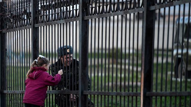 A Ukrainian soldier speaks to his daughter through a gate as he waits inside the Sevastopol tactical military brigade base near Belbek in Sevastopol on March 3, 2014. Russian forces have given Ukrainian soldiers an ultimatum to surrender their positions in Crimea or face an assault, a Ukrainian defence ministry spokesman said. 'The ultimatum is to recognise the new Crimean authorities, lay down our weapons and leave, or be ready for an assault,' said Vladyslav Seleznyov, the regional ministry spokesman for the Crimea.