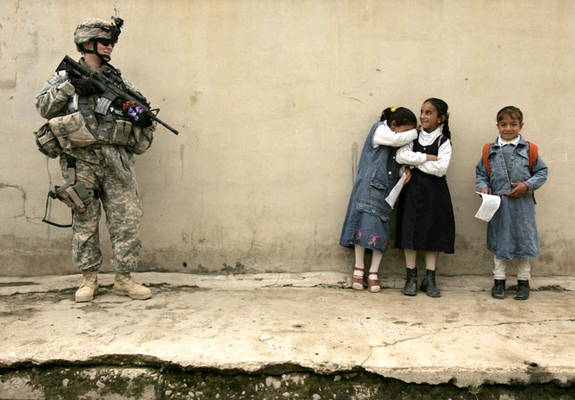16 April, 2007. A girl becomes embarrassed after giving flowers to a female US soldier on duty in the northern Iraqi city of Mosul.