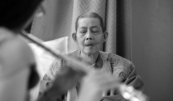 In a nursing home in Chinatown, Meredith Traver plays ancient Chinese folk tunes on the flute for Kai Sui Fung, 60. He is dying of lung cancer.