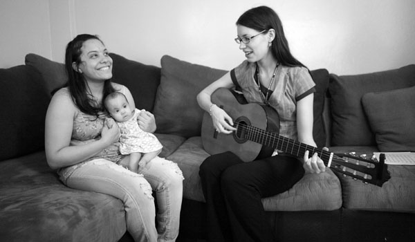 Meredith Traver playing guitar for 6-month-old Cecilia Havre and her mother, Chantel Vasquez. Cecilia has a genetic disorder called Trisomy 18, which claims half its victims before the first week of life.