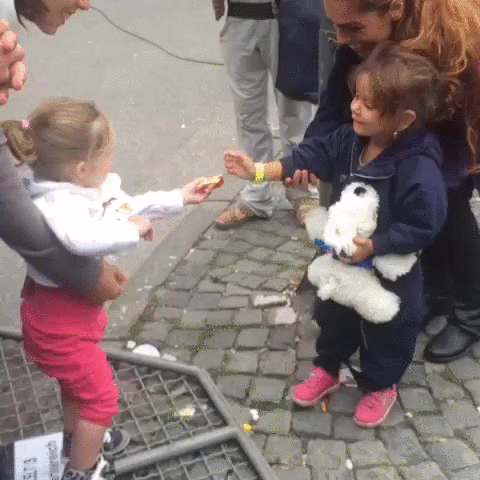 A young German girl greets a newly arrived young refugee girl
