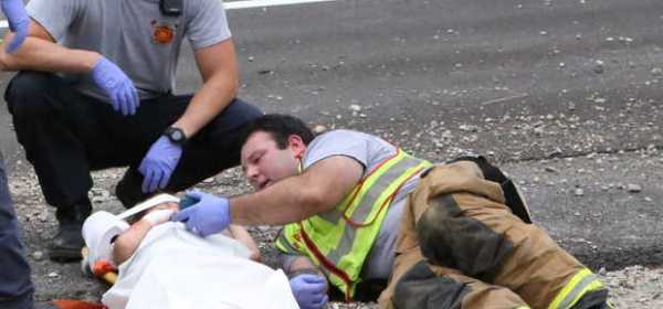 firefighter Casey Lessard, right, plays a cartoon on his cellphone to calm an injured child