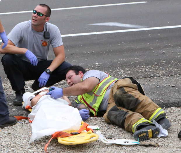 firefighter Casey Lessard, right, plays a cartoon on his cellphone to calm an injured child