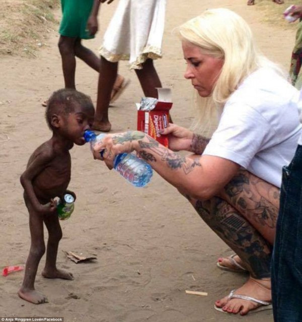 Aid worker giving water to a starving Nigerian boy.